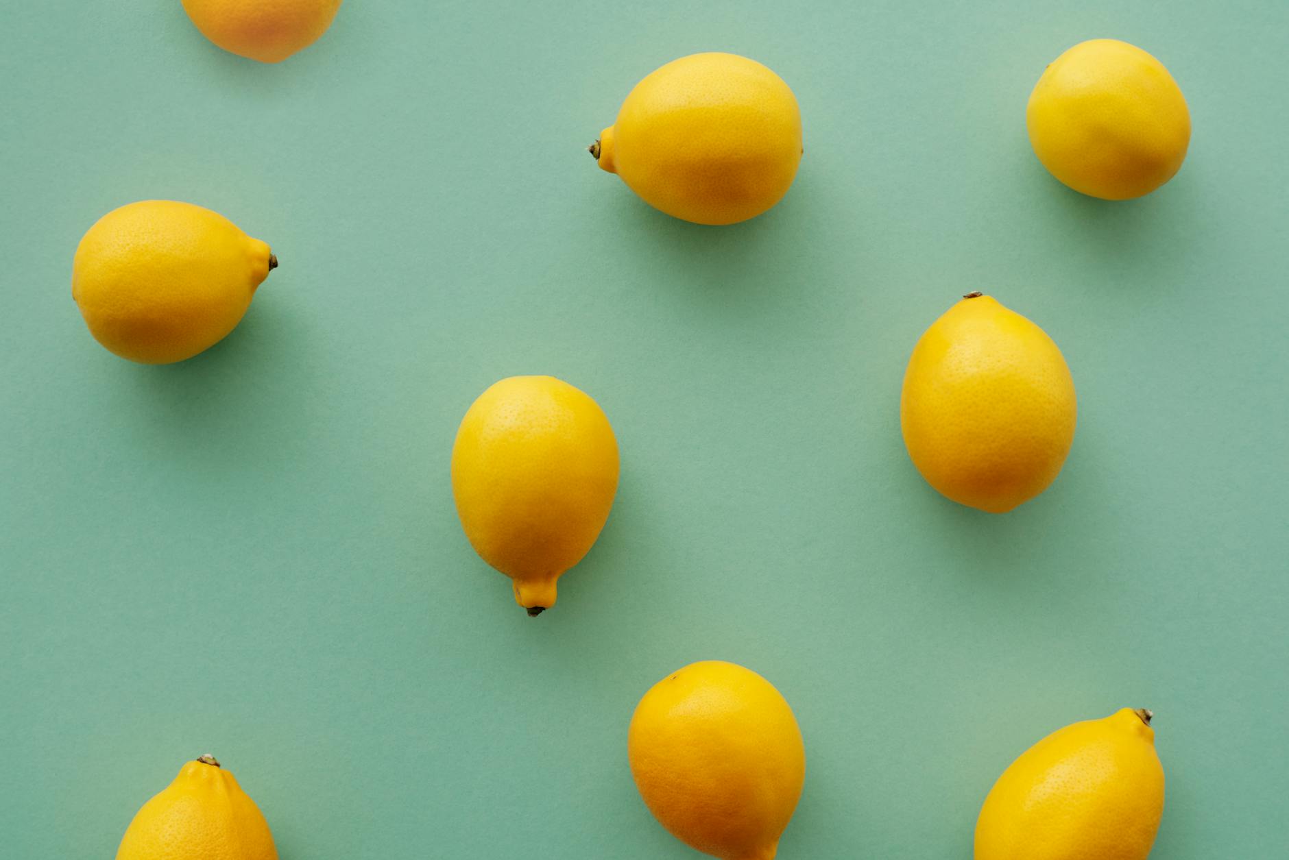 Bright yellow lemons on a soft pastel green background, symbolizing fresh starts and taking your own pace