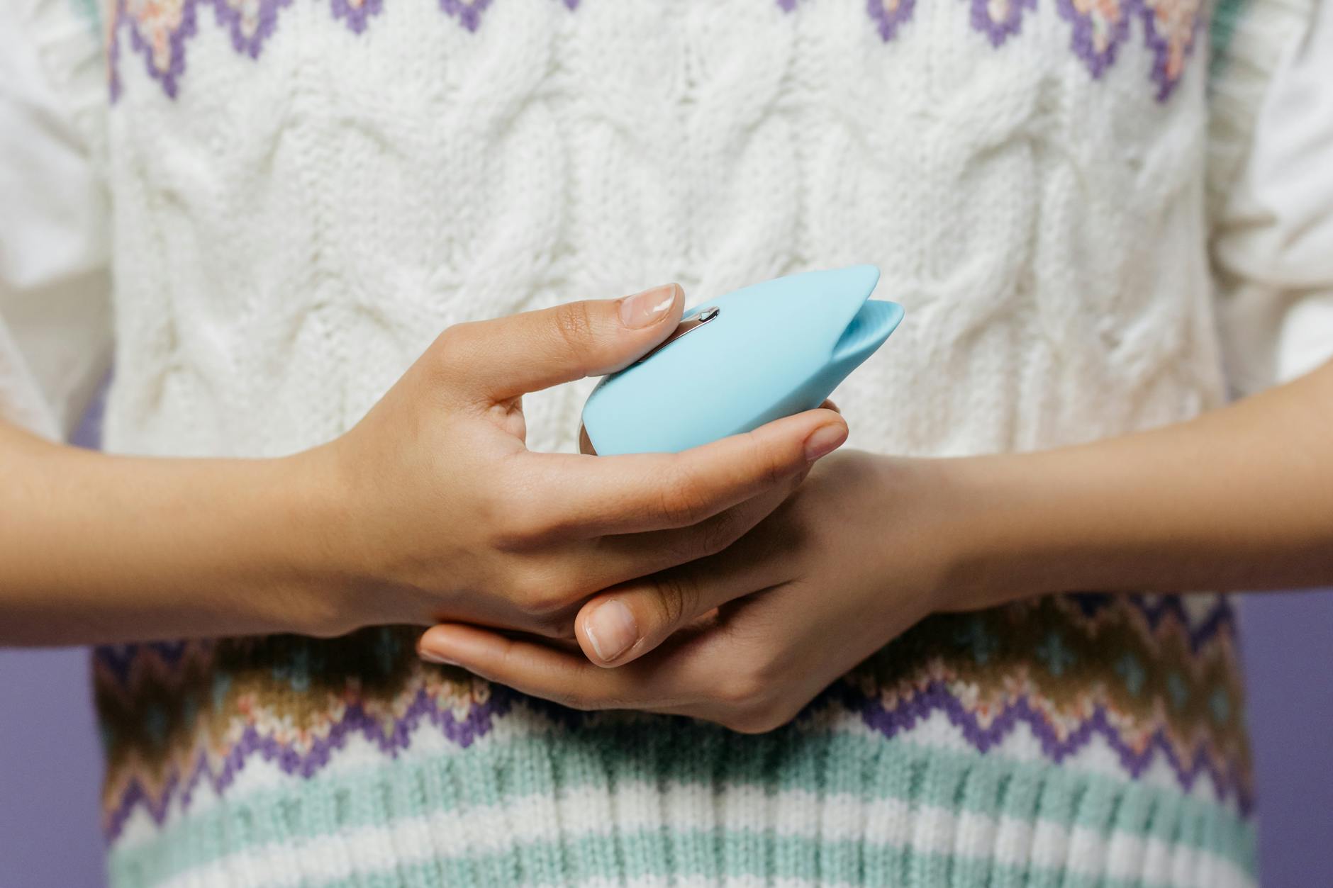 Hands holding a lemon vibrator against a knitted sweater, representing intimate reconnection
