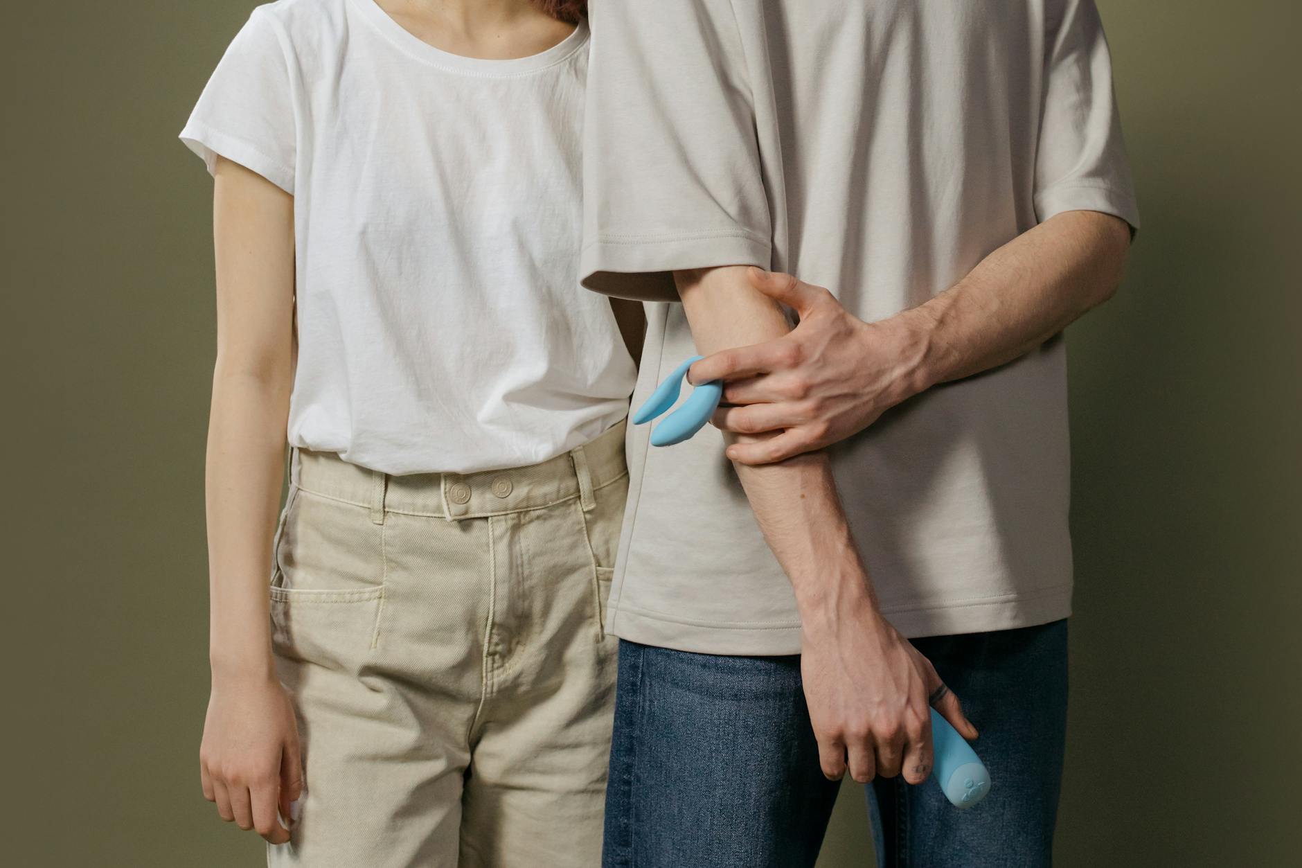 Close-up of hands holding a sleek blue clitoral vibrator, representing modern intimate wellness tools.