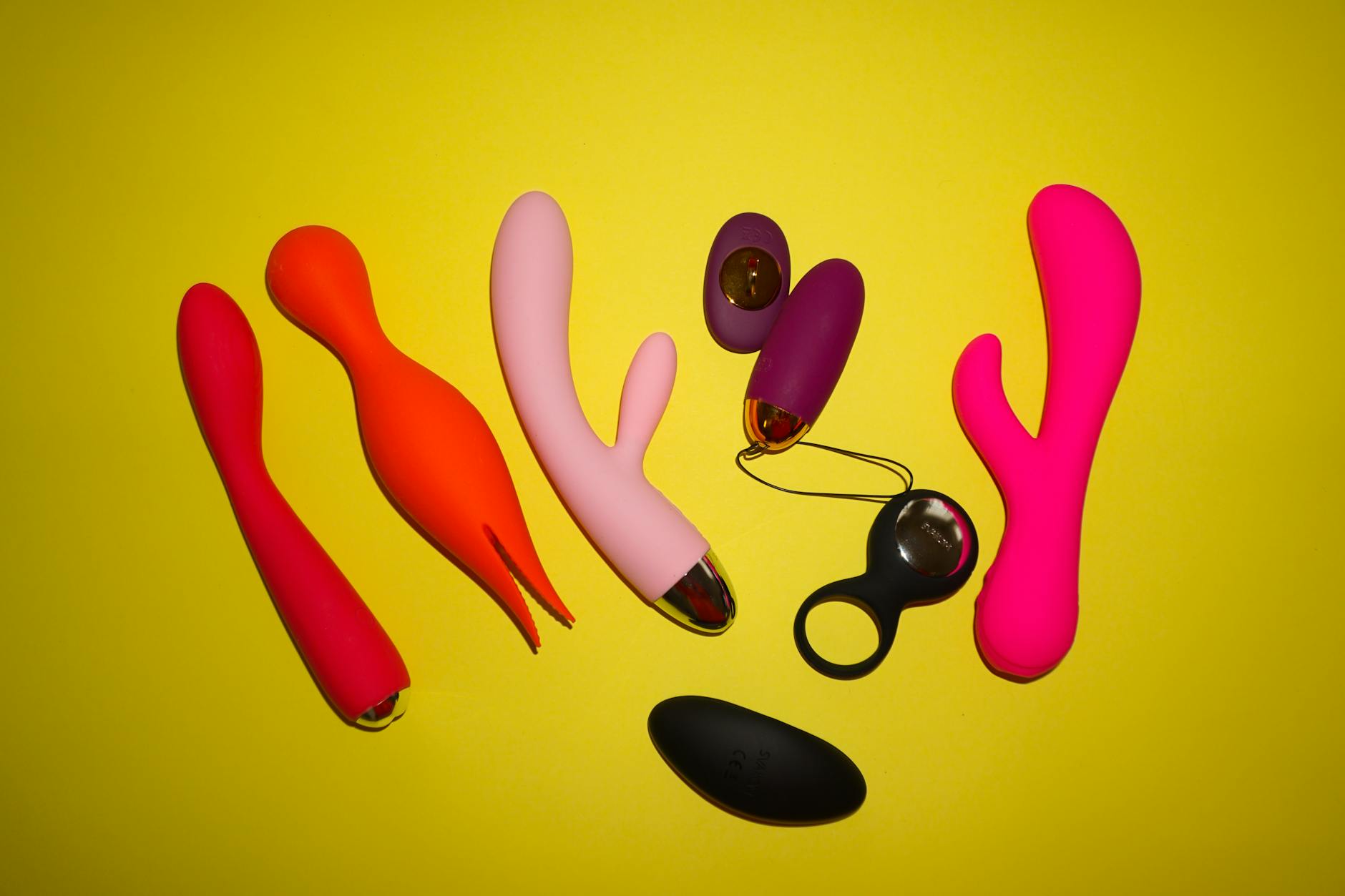 Woman holding blue and pink vibrators in a contemplative manner